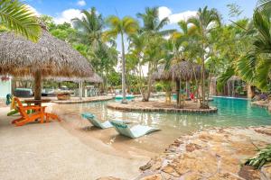 a resort with a pool with chairs and palm trees at KonTiki Falls! Jupiter's Exclusive Private Resort in Jupiter