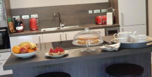 a kitchen counter with a bowl of fruit and a cake at Bluebell Lodge in Errol +4 photos