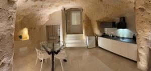 a kitchen with a glass table in a stone wall at IL Nido nella Roccia in Matera +27 photos