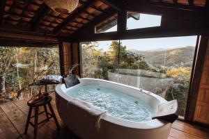 a bath tub in a room with a large window at Smart Hotel Reserva Santo Antônio do Pinhal in Santo Antônio do Pinhal +108 photos