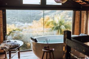 a bath tub in a room with a large window at Smart Hotel Reserva Santo Antônio do Pinhal in Santo Antônio do Pinhal