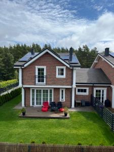 a brick house with a green lawn at Melnrage Beach cozy apartments & terrace - pine view sea entry in Klaipėda