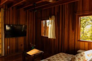 a bedroom with a television and a bed and a table at Chalé Eucalipto in Uberlândia