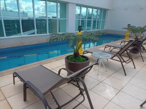 a group of chairs and tables next to a swimming pool at Flat Particular Marizienne Hotel Saint Moritz 86 in Brasília