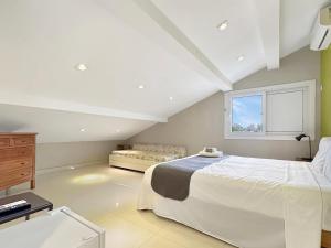 a bedroom with a white bed and a window at 200m do mar - AC - 1 Suite - Piscina - Churrasqueira in Guarujá