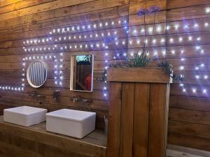 a bathroom with two sinks and lights on a wooden wall at Mallard - 5m Luxury Bell Tent at Tregonetha Lake - Tylda Tents in Saint Columb Major +29 photos