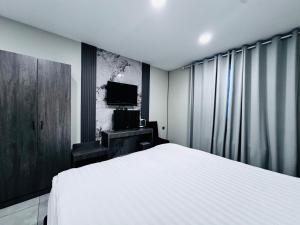 um quarto com uma cama branca e uma tv em Lofty Hotel em Ulaanbaatar