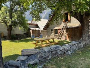 a wooden picnic table in front of a stone wall at Les Écrins d'or - Maison Les Deux Alpes in Les Deux Alpes