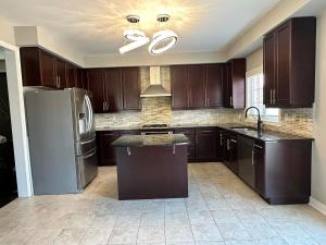 a kitchen with brown cabinets and a stainless steel refrigerator at Luxurious Villa 3 Living Rooms, 1 sofa bed, 4 bedrooms, 4 Beds, 4 Toilets, 1 hour To Toronto in Oshawa