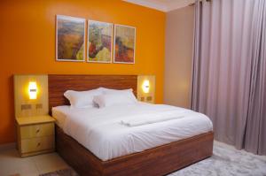 a bedroom with a bed and two pictures on the wall at White Cottage Suites in Kampala