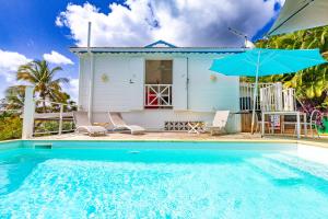 a house with a swimming pool and a blue umbrella at TOUDOU DOUDOU in Deshaies