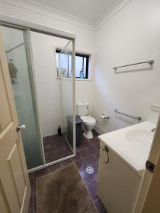 a bathroom with a shower and a sink and a toilet at Solitary Islands Golf House in Woolgoolga +15 photos