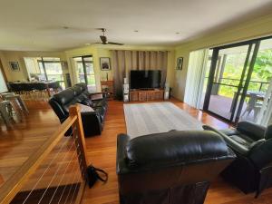 a living room with leather furniture and a flat screen tv at Solitary Islands Golf House in Woolgoolga