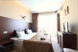 een hotelkamer met een bed en een groot raam bij Първа линия Апартаменти in Pomorie