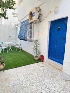 a blue door on a building with a green yard at RDC de villa Marsa cité tabbak in La Marsa