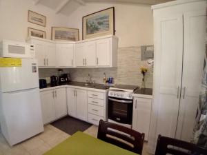 a kitchen with white cabinets and a white refrigerator at The Pool House in Saint Philip