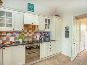 a kitchen with white cabinets and black counter tops at Lynwood in Boscastle