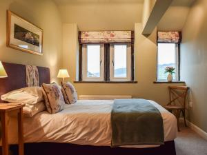 a bedroom with a bed and two windows at Trough Cottage - Uk48424 in Holmfirth +14 photos