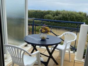 a table and two chairs and a vase with flowers on a balcony at Appartement 2 personnes - Face plage Valentin - FR-1-843-24 in Le Croisic
