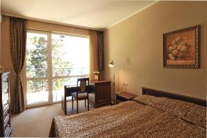 een slaapkamer met een bed, een bureau en een raam bij Първа линия Апартаменти in Pomorie +50 foto's