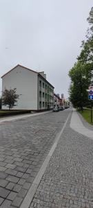 una strada vuota con un grande edificio bianco di Senamiesčio butas a Klaipėda