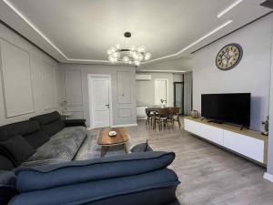 a living room with a couch and a clock on the wall at BST Batumi Leo in Angisa
