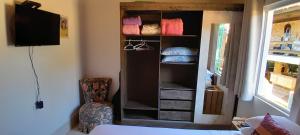 a room with a closet with a tv and a chair at Descanso merecido in Morretes