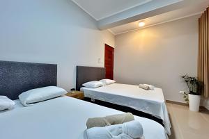 Un dormitorio con dos camas y una silla. en Depa a 5min centro 2HAB con A/C Terraza y Parrilla, en Tarapoto