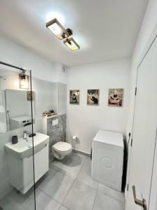 a white bathroom with a toilet and a sink at SeaTok & Stay in Costinesti +18 photos