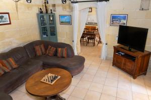 a living room with a couch and a television at Tal-Masklu farmhouse in Għarb