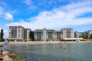een groep mensen in het water voor een strand bij Първа линия Апартаменти in Pomorie