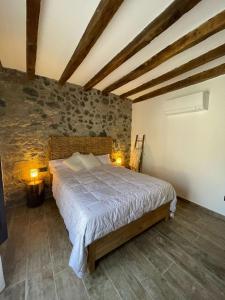 a bedroom with a large bed in a stone wall at El Portalet de Can Rialla in Santa Pau