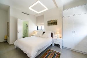 Dormitorio blanco con cama blanca y armario blanco en Sunny Luxury Apartments en Tel Aviv