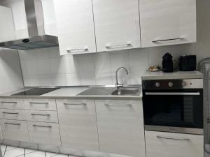 a kitchen with white cabinets and a sink at La casa Bianca di Luca in Fiumicino