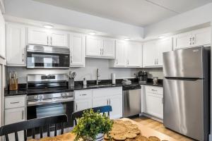 a kitchen with white cabinets and a stainless steel refrigerator at Poolside Near the Landing For 2 in Branson