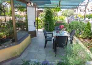 a patio with a table and chairs in a garden at Apartments Masek in Poreč