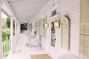 a white porch with chairs and tables on it at The Cottage House in Thompson