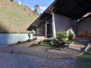 a house with a stone walkway next to a lake at Casa de Campo em Teresópolis in Teresópolis