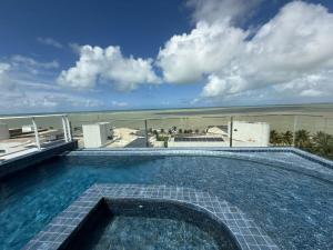 a swimming pool on top of a building with the beach at Studio Mobiliado com Vista Mar a 30m da Praia de Ponta de Campina in Cabedelo