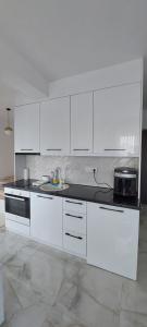a kitchen with white cabinets and a black counter top at Apartman Vaske 1 in Brčko