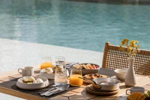 a table with food and drinks on a table by a pool at AMĀRIA Beach Resort by NOMÉE Hospitality Group in Kamari +31 photos