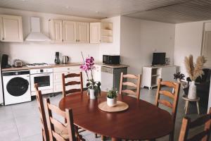 a kitchen with a wooden table and chairs and a kitchen with white cabinets at Grange Les Sens Ciel in Saint-Mesmin