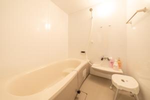 a white bathroom with a tub and a toilet at Sanada Maru - Entire traditional Japanese house in Kaizuka