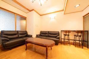 a living room with two leather couches and a coffee table at Sanada Maru - Entire traditional Japanese house in Kaizuka +74 photos