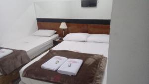 deux lits dans une chambre d'hôtel avec des serviettes dessus dans l'établissement Hotel Las Vegas Guarulhos, à Guarulhos