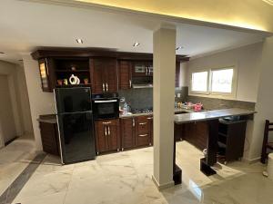 a kitchen with a black refrigerator and wooden cabinets at Beach House - Ramsis Village in ‘Izbat aţ Ţayrīyah