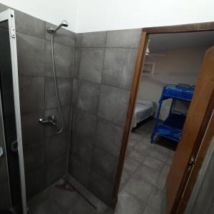 a shower with a glass door and a room with a bed at Complejo Corrientes Depto 4 in Jesús María