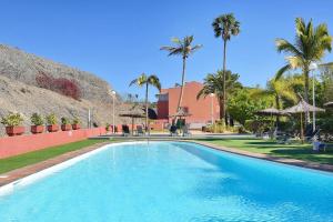 a large swimming pool with palm trees and a building at Puerto Marina 10 - Pasito Blanco in San Bartolomé de Tirajana