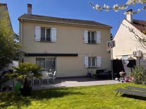 ein großes Haus mit einer Terrasse im Hof in der Unterkunft Maison Familiale au coeur d'aulnay sud, proche gare, aéroport CDG, Parc des expositions in Aulnay-sous-Bois