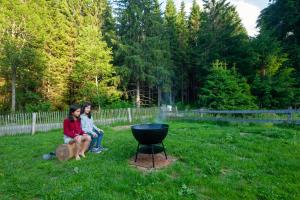 due donne sedute sull'erba accanto a una griglia di Landhaus Auerling am Wald - Ruhige Lage, Wander- und Skiparadies a Sankt Lambrecht